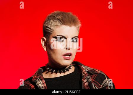 Cheveux courts blond Angry rock girl sur fond rouge Banque D'Images