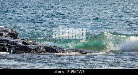 Des vagues d'eau vert claire éclabousse contre une rive rocheuse du lac supérieur; Grand Portage, Minnesota, États-Unis d'Amérique Banque D'Images