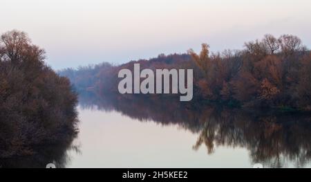 Arbres avec feuilles tombées le long des rives de la rivière Oka à la fin de l'automne au coucher du soleil. Banque D'Images