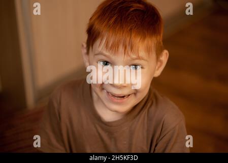 Un jeune garçon souriant pour l'appareil photo à la maison. Banque D'Images