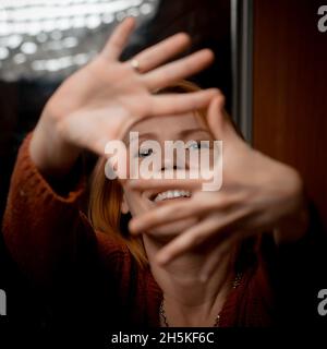 Une femme d'âge moyen contentée tient ses doigts comme un appareil photo. Banque D'Images