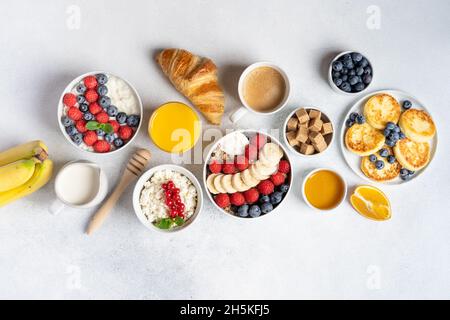 Petit déjeuner servi le matin : crêpes, porridge, fromage cottage, granola, muesli,jus d'orange, thé, café, fruits et baies. Banque D'Images