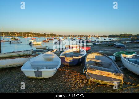 Bateaux à rames et yachts à Itchenor, Chichester Harbour, dans la lumière du soir à marée basse. Banque D'Images