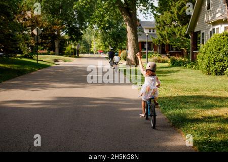 Un petit enfant qui fait du vélo en famille lève la main Banque D'Images