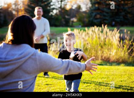 Une jeune famille joue dans le parc avec un football lors d'une belle journée d'automne; St. Albert, Alberta, Canada Banque D'Images