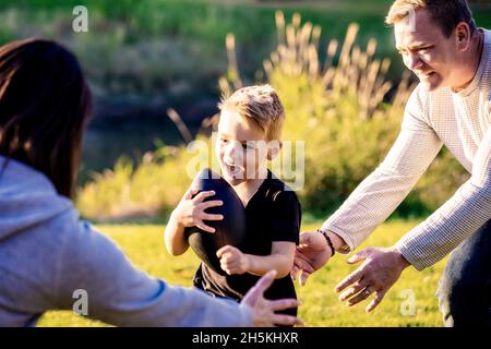 Une jeune famille joue dans le parc avec un football lors d'une belle journée d'automne; St. Albert, Alberta, Canada Banque D'Images