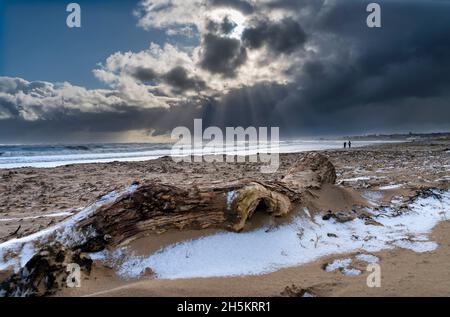 Nuages de tempête se formant au-dessus de l'océan avec un mouette en vol au-dessus de la plage avec de la neige sur le sable à marée basse; Whitburn, Tyne et Wear, Angleterre Banque D'Images