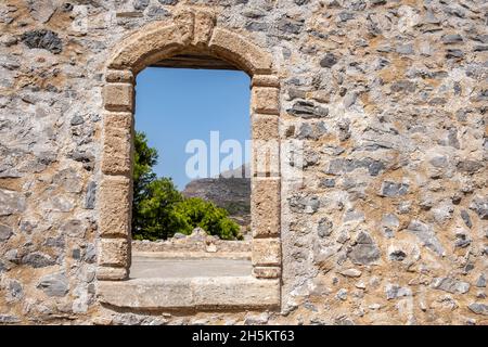 Cadre de fenêtre avec arche sur un mur de pierre au château vénitien Fortezza sur l'île de Chora Kythira, Grèce.Vue depuis l'ouverture du monument Kythera Kithira. Banque D'Images