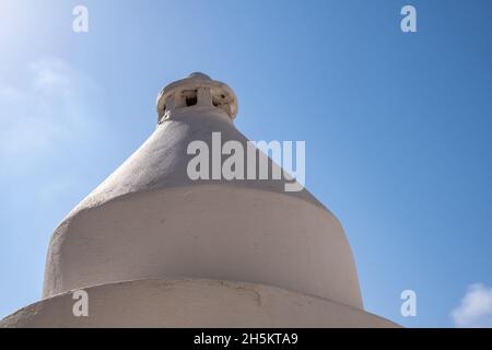 Cheminée ronde blanchie à la chaux sur le toit du bâtiment, île grecque, Grèce.Encerclez la construction extérieure de Smokestack sur le toit d'une maison.Fond bleu ciel Banque D'Images