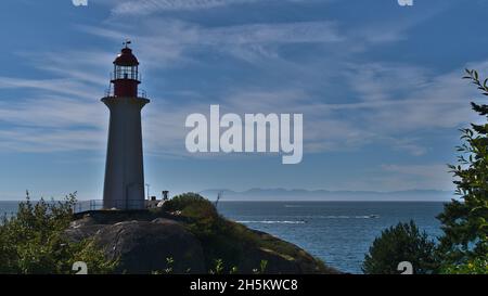 Vue sur le phare de point Atkinson sur les rives du parc Lighthouse à West Vancouver (Colombie-Britannique), Canada avec l'océan Pacifique et les montagnes. Banque D'Images