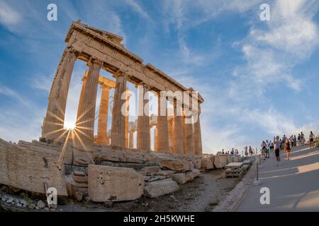 Temple Parthénon au site archéologique de l'Acropole. Le soleil brille à travers les anciennes colonnes. Vue panoramique en angle, jour ensoleillé, ciel bleu ciel nuageux Banque D'Images