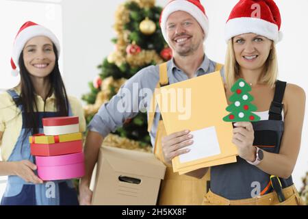 Groupe de posters en chapeaux de père noël rouges tenant des lettres et des boîtes avec des cadeaux Banque D'Images