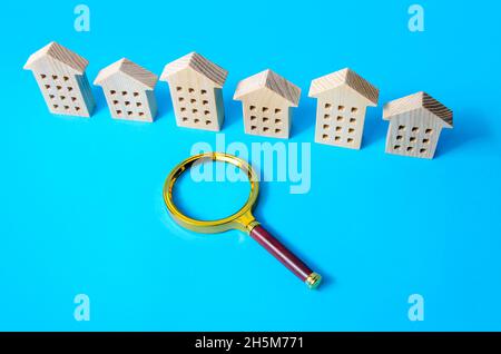 Une rangée de figures de maisons et une loupe.Le concept de trouver un appartement à louer ou à acheter.Achat ou location de logements.Serveur de realtor Banque D'Images