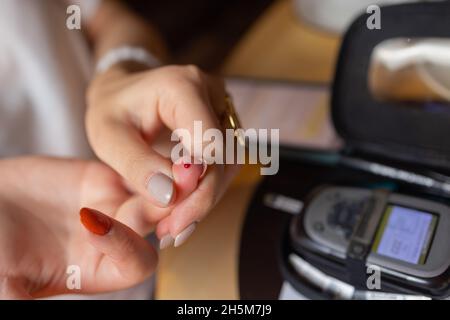 Femme test pour l'hyperglycémie.Femme tenant un dispositif pour mesurer le sucre dans le sang Banque D'Images