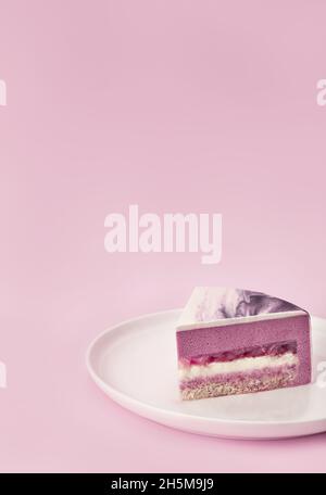 Délicieuse tranche de gâteau de mousse de litchi et de framboise avec les couches et la texture affichées sur fond lilas.Menu du restaurant et concept de confiserie.Gros plan.Copier l'espace. Banque D'Images