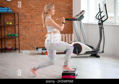 Jeune femme enceinte s'entraîner avec un stepper aérobie dans la salle de gym Banque D'Images