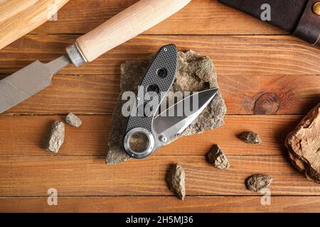 Couteau de poche pliant avec poignée en caoutchouc sur table en bois Banque D'Images