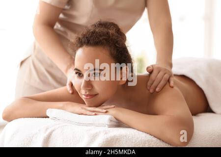 Belle femme afro-américaine recevant un massage par un thérapeute dans le salon de spa Banque D'Images