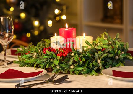 Belle couronne de GUI avec bougies sur table servi pour le dîner de Noël Banque D'Images