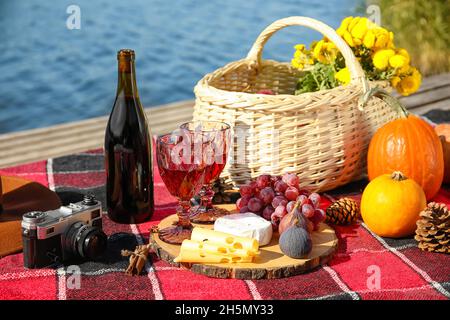 Une cuisine savoureuse avec du vin pour un pique-nique romantique près de la rivière le jour de l'automne Banque D'Images