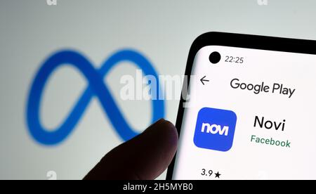Portefeuille numérique de l'application Novi dans Google Play vu sur l'écran du smartphone, le doigt pointant dessus et le logo FACEBOOK META flou sur l'arrière-plan. Banque D'Images