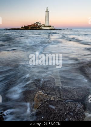 Débit d'ondes de l'autre côté de l'île de St Mary's Causeway au crépuscule, avec St Mary's Lighthouse derrière, sur la côte de la baie de Whitley Tyneside. Banque D'Images