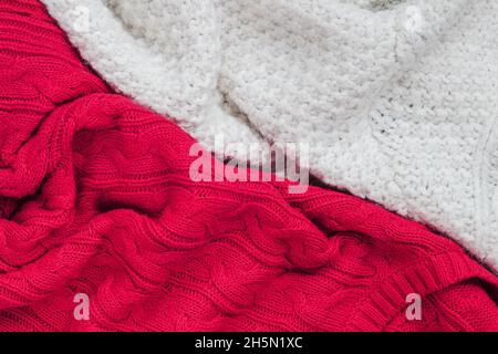 Texture de pull-overs tricotés, blanc et rouge.Pose à plat, gros plan.Concept de shopping, fabrication, passe-temps Banque D'Images