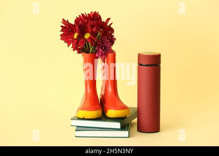 Bottes en caoutchouc, fleurs, thermos et livres sur fond de couleur Banque D'Images