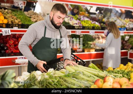 L'assistant commercial met des légumes et des fruits sur le comptoir du supermarché Banque D'Images