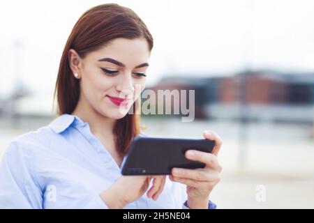 Jeune rouge caucasien collier blanc travailleur messagerie sur téléphone mobile à l'extérieur Banque D'Images