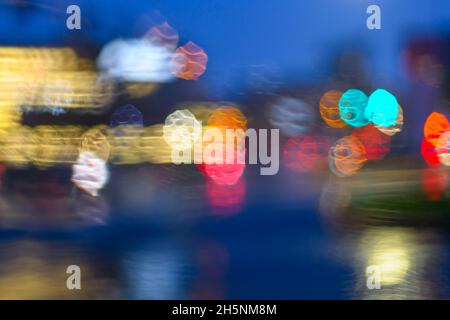 Trafic sous la pluie au crépuscule créant des motifs bokeh dans plusieurs couleurs Banque D'Images