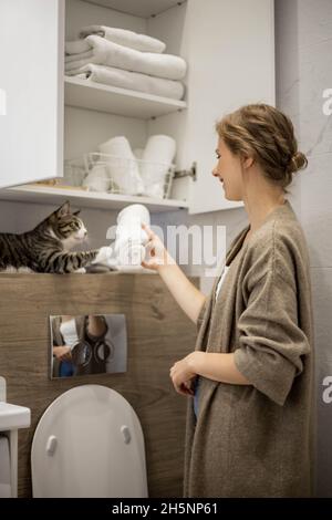 Femme mettant ou affichant soigneusement une serviette blanche enroulée propre en coton biologique. Banque D'Images