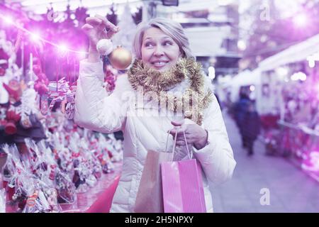 Bonne femme mûre en guirlande avec des jouets de Noël à la foire Banque D'Images