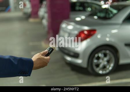 Gros plan main un homme appuyez sur le bouton de la télécommande pour verrouiller et déverrouiller la porte de la voiture Banque D'Images