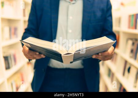 étudiant dans une librairie ou une bibliothèque. l'homme lit le livre dans une librairie.Un homme d'affaires achète un livre en cadeau. Banque D'Images
