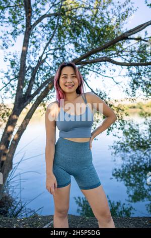 Jeune femme asiatique à Dappled lumière du soleil assis sur la rive d'un lac idyllique Banque D'Images