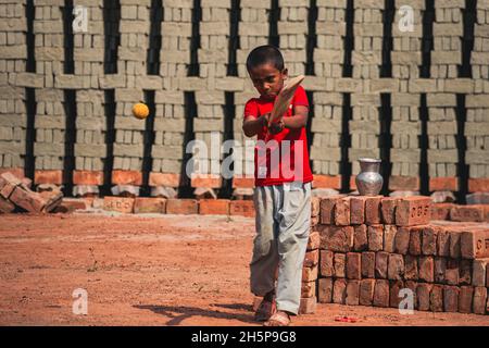 Un garçon jouant au cricket dans le brickfield Banque D'Images