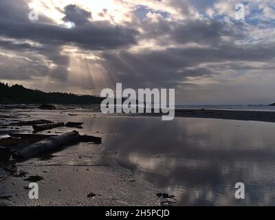 Belle vue de long Beach sauvage sur la côte du Pacifique avec un ciel spectaculaire reflété dans l'eau et les silhouettes des gens près de Tofino, C.-B., Canada. Banque D'Images