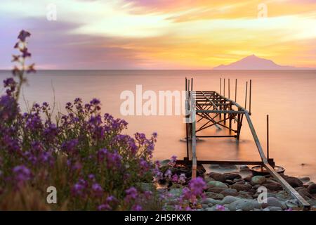 Coucher de soleil sur la mer avec un fond de Mont Athos et une jetée sur une plage Banque D'Images