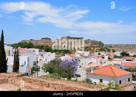 Une vue sur le château et les bâtiments de la ville avec un joli arbre Jacaranda en fleurs au premier plan, Castro Marim, Algarve, Portugal, Europe. Banque D'Images