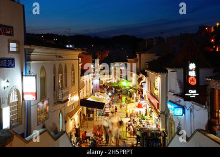 Portrait de la R 5 de Outubro shopping street dans la soirée avec les touristes appréciant les paramètre, Albufeira, Portugal, Europe. Banque D'Images