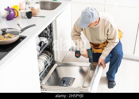 Vue de l'homme en réparation générale lave-vaisselle dans la cuisine Banque D'Images