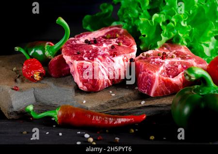 Set de nourriture pour un pique-nique.Biftecks de bœuf, la ribeye est prête à cuire au barbecue.Deux steaks de ribeye frais classiques sur pierre avec des herbes poivrières au-dessus de su de pierre grise Banque D'Images