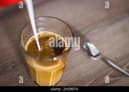 Lait versé dans un café instantané dans un verre avec une cuillère, à Prague, République tchèque, 9 novembre 2021.(Photo CTK/Martin Macak Gregor) Banque D'Images