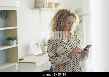Les femmes adultes ne peuvent utiliser que leur téléphone mobile pour envoyer des messages à domicile.Femme moderne utilise le cellulaire pour envoyer des SMS et des messages.Une seule femme style de vie intérieur en livin Banque D'Images