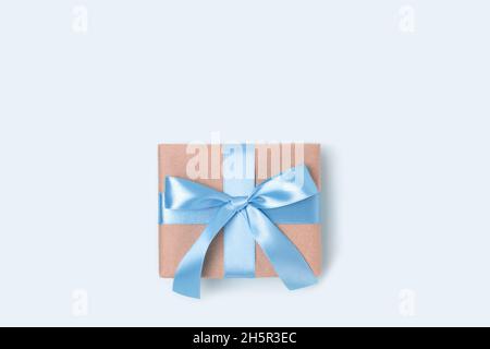 Boîte cadeau sur fond bleu.Cadeau attaché avec ruban.Concept de fête minimaliste avec espace de copie. Banque D'Images