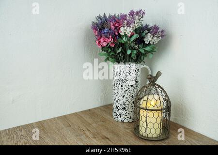 Cage à oiseaux avec bougie et décoration florale sur fond de bois Banque D'Images