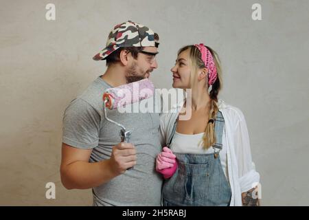 Une jeune famille heureuse fait une réparation de rêve à l'intérieur de la maison avec ses propres mains.Mari et femme peignent le mur de la chambre Banque D'Images