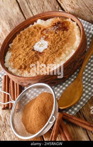 Riz au lait recouvert de cannelle, de sucre et de beurre dans un bol sur la table. Vertical Banque D'Images