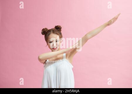 Gai drôle jeune femme 20s faisant dab hip hop danse mains gestuelle, sur pastel rose couleur fond portrait studio Banque D'Images